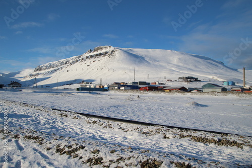 Longyearbyen town panorama in Svalbard, Norway. Remote arctic settlement with colorful houses, traditional wooden architecture, industrial heritage under winter snow and majestic polar mountains.
