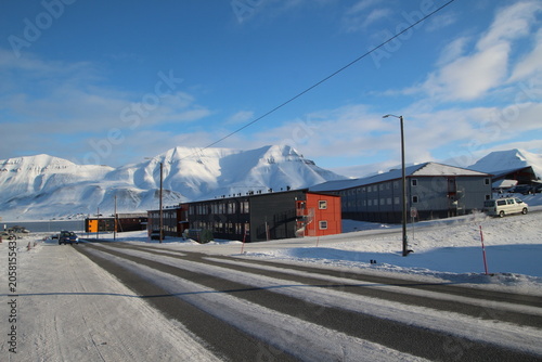 Longyearbyen town panorama in Svalbard, Norway. Remote arctic settlement with colorful houses, traditional wooden architecture, industrial heritage under winter snow and majestic polar mountains.
