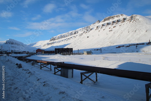 Longyearbyen town panorama in Svalbard, Norway. Remote arctic settlement with colorful houses, traditional wooden architecture, industrial heritage under winter snow and majestic polar mountains.