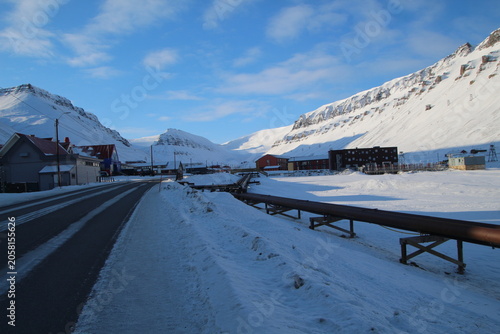 Longyearbyen town panorama in Svalbard, Norway. Remote arctic settlement with colorful houses, traditional wooden architecture, industrial heritage under winter snow and majestic polar mountains.