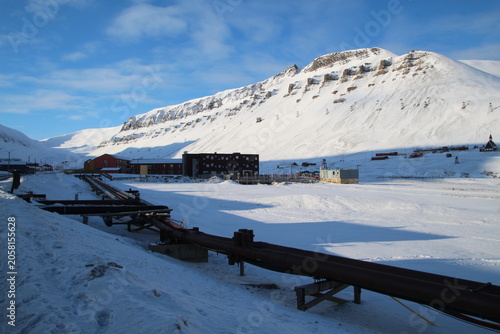 Longyearbyen town panorama in Svalbard, Norway. Remote arctic settlement with colorful houses, traditional wooden architecture, industrial heritage under winter snow and majestic polar mountains.