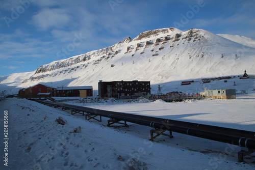 Longyearbyen town panorama in Svalbard, Norway. Remote arctic settlement with colorful houses, traditional wooden architecture, industrial heritage under winter snow and majestic polar mountains.