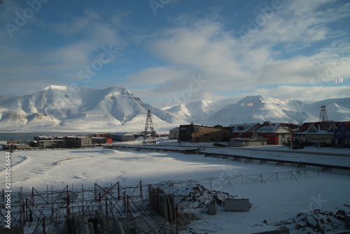 Longyearbyen town panorama in Svalbard, Norway. Remote arctic settlement with colorful houses, traditional wooden architecture, industrial heritage under winter snow and majestic polar mountains.