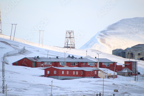 Longyearbyen town panorama in Svalbard, Norway. Remote arctic settlement with colorful houses, traditional wooden architecture, industrial heritage under winter snow and majestic polar mountains.