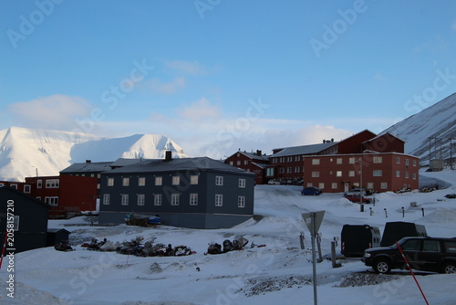 Longyearbyen town panorama in Svalbard, Norway. Remote arctic settlement with colorful houses, traditional wooden architecture, industrial heritage under winter snow and majestic polar mountains.