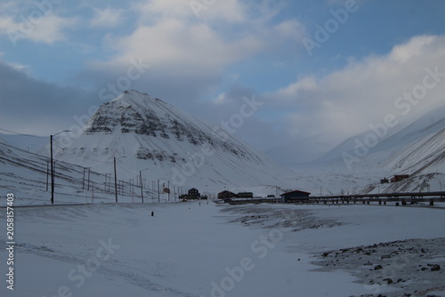 Longyearbyen town panorama in Svalbard, Norway. Remote arctic settlement with colorful houses, traditional wooden architecture, industrial heritage under winter snow and majestic polar mountains.