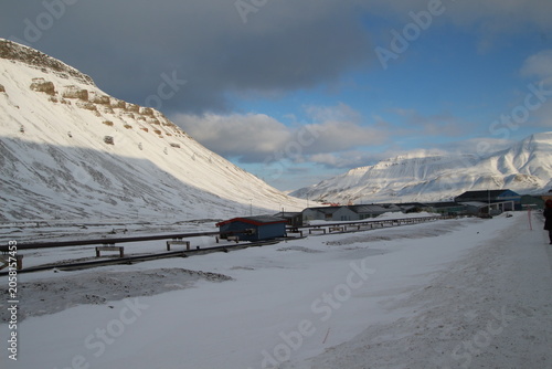 Longyearbyen town panorama in Svalbard, Norway. Remote arctic settlement with colorful houses, traditional wooden architecture, industrial heritage under winter snow and majestic polar mountains.