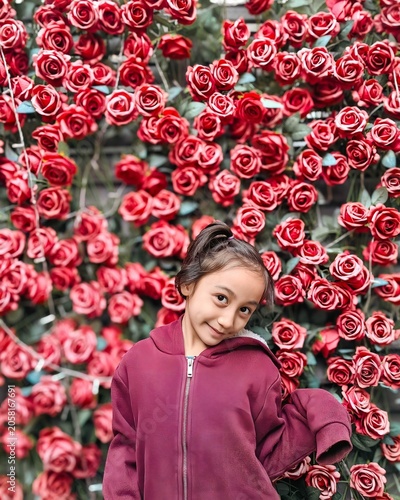 Portrait of a little girl wearing sweater same as her roses background in outdoor