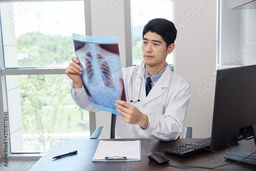 Foto Doctor Examining Chest X-Ray in Medical Office