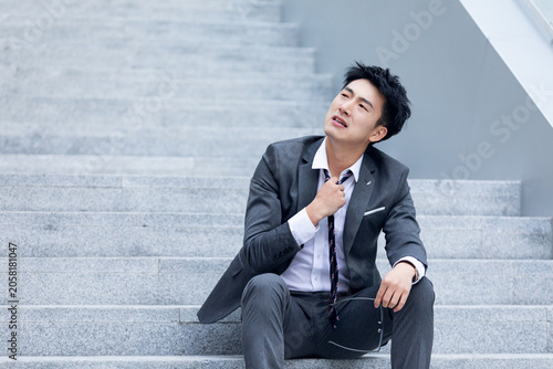 Valokuva Exhausted businessman sitting on stairs after stressful workday