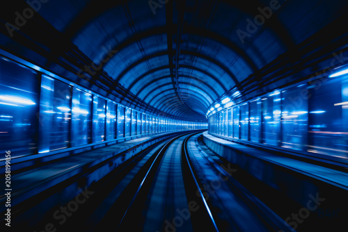 A curved modern urban rail tunnel with blue lighting, showing a sense of speed and architectural structure.