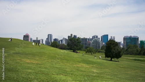 Time-lapse of people moving through Olympic Park in Seoul, Korea, with cityscape background and green meadow