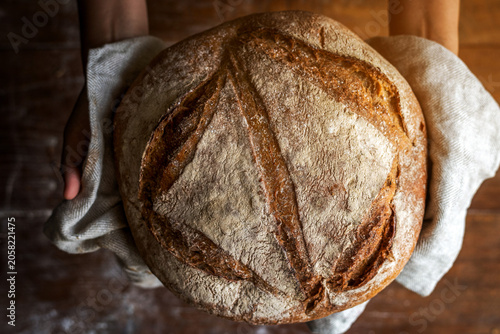 Obraz na plátne Rustic artisan sourdough bread held in gloved hands