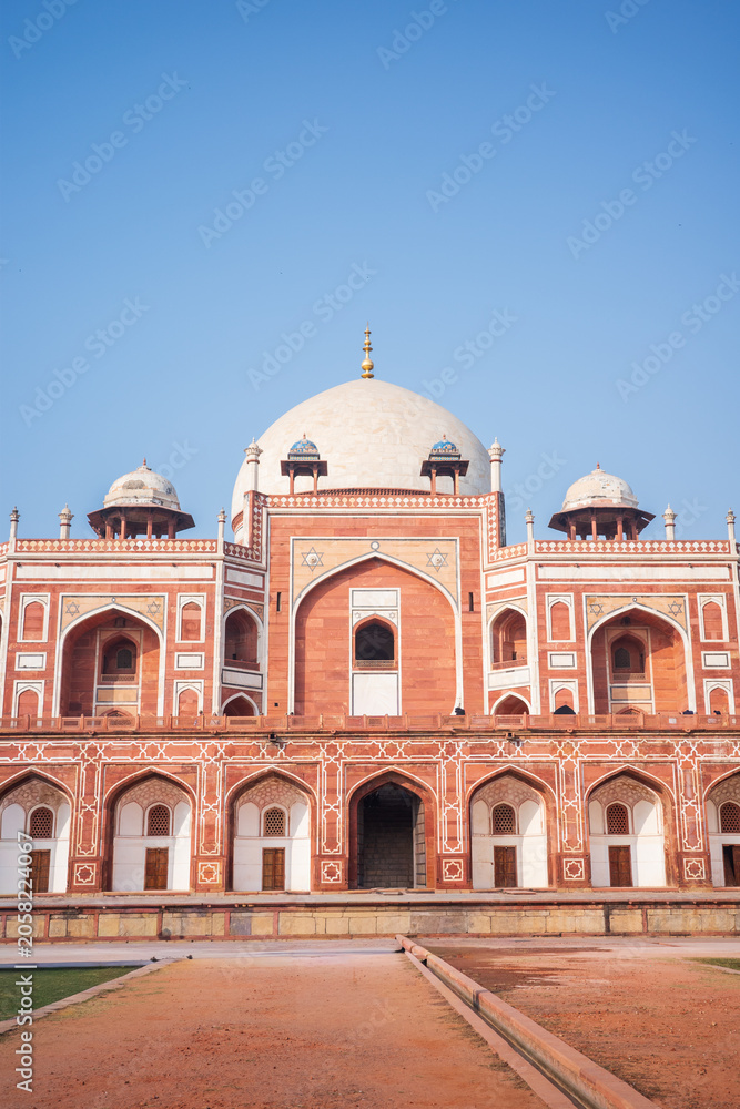 Naklejka premium Elegant vertical photograph of Humayun’s Tomb in New Delhi, India, featuring its iconic white marble dome, red sandstone facade, ornate arches, and perfectly symmetrical Mughal architecture