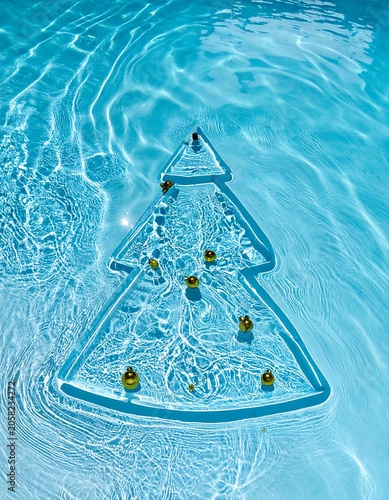 A Christmas tree-shaped decoration floats on rippling water's surface