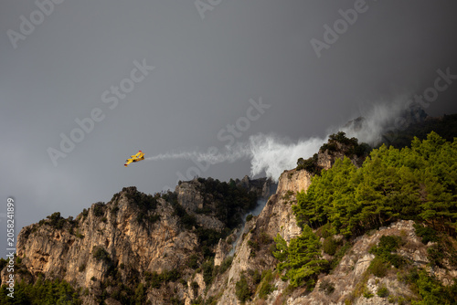 Photos POSITANO, ITALY - OCTOBER 01, 2018: A yellow Canadair firefighting airplane drops a water on a raging forest fire