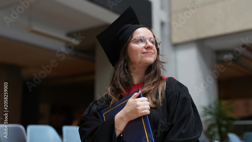 young female graduate with diploma looking up smiling, bright future, higher education