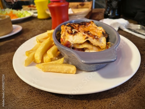 Close-up of a delicious baked meat lasagna with a side of crispy french fries