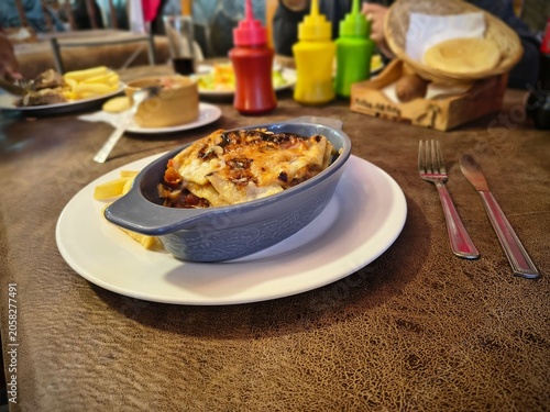 Close-up of a delicious baked lasagna served in a blue ceramic dish at a restaurant table