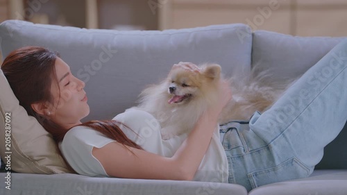 Asian woman with dog on sofa in home for bonding, relaxing and playing together in living room. Pet owner, best friend and happy person with pet on couch for affection, petting and love.