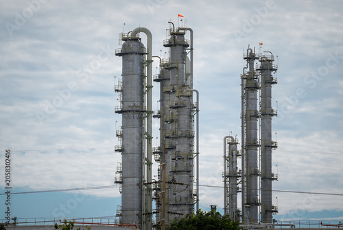 Oil refinery distillation column industrial plant petrochemical pipeline steel tower processing unit chemical industry under cloudy sky, complex infrastructure for fuel production