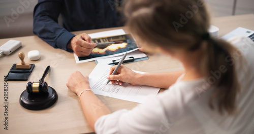 Insurance Agent And Client Review Claim Forms During Property Damage