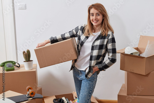 Woman carrying packed box while unpacking belongings