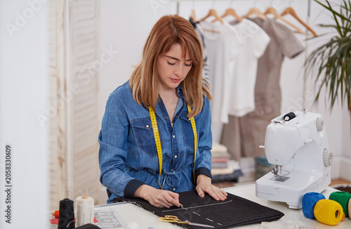 Seamstress sewing fabric on machine in clothing studio