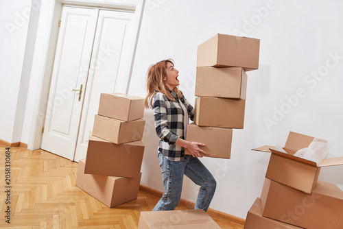Woman struggling with unstable stack of moving boxes