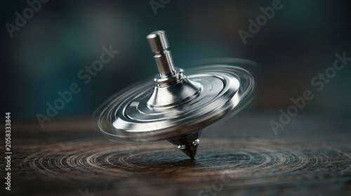 Close-up of a shiny metal spinning top spinning on a dark wooden table.