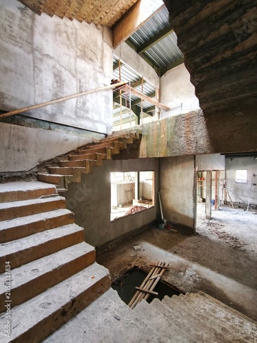 Jakarta City, Indonesia - June 14, 2026: Unfinished exposed cast concrete staircase without railing connecting floors inside residential house building interior under wall construction stage
