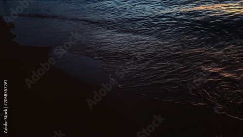 Obraz na plátně Gentle ocean waves illuminated by soft golden sunset light.