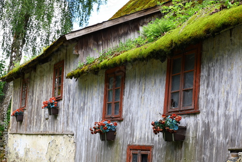 Photos Traditional wooden house with moss-covered roof in rural countryside