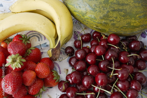 Fresh strawberries, bananas, cherries and melon arranged on kitchen table for healthy eating