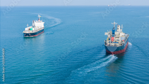 Billede på lærred Two large cargo ships navigating together through the deep blue ocean, representing a maritime transport fleet, global logistics network, and international shipping trade industry