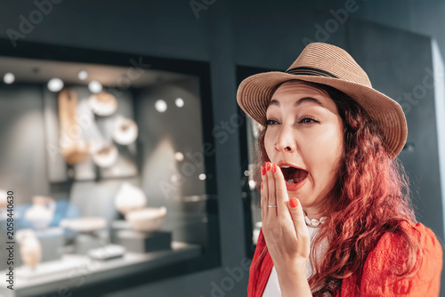 Foto Young woman covering her mouth yawning from boredom and fatigue while looking at