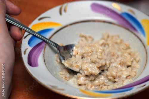 Ceramic bowl of oatmeal porridge with a metal spoon, ready for a healthy breakfast