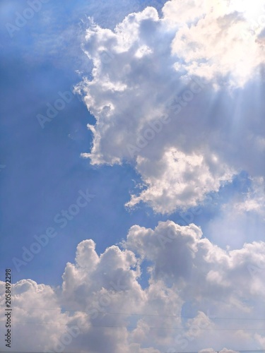 Photography Beautiful blue sky background with fluffy white cumulus clouds and bright sun ra