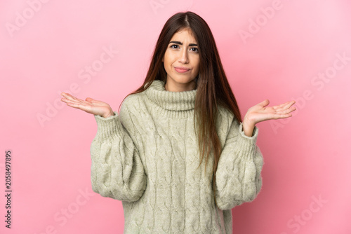 Fotografía Young caucasian woman isolated on pink background having doubts while raising ha