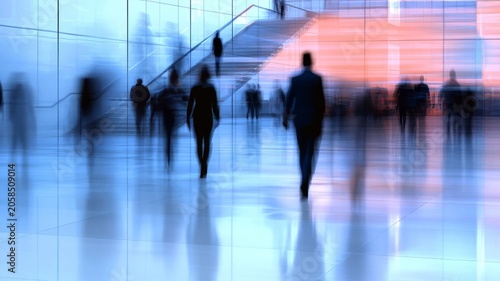 Blurred silhouettes of people walking inside a modern office lobby architecture interior space.