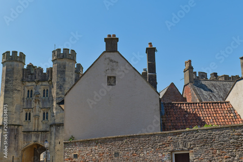 Obraz na płótnie A historic stone castle gatehouse stands left of several houses with gabled roof