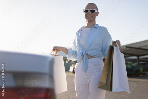 Foto Woman smiling after a successful shopping spree, holding retail bags near her ca