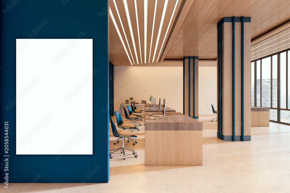 Naklejka premium Blank vertical poster mockup on blue wall in modern corporate office interior with wooden desks, clean design, bright lighting and contemporary room ambience. 3D Rendering
