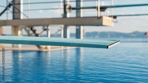 A professional diving springboard curving over calm blue pool water.