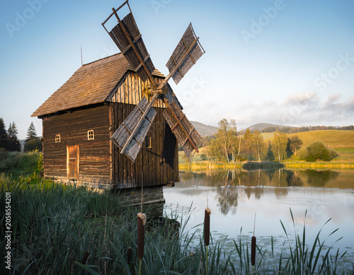 Old Slovak windmill with a thatched roof from the old daysby lake