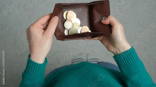 High angle slow motion of a person holding an open brown leather wallet filled with various euro coins.