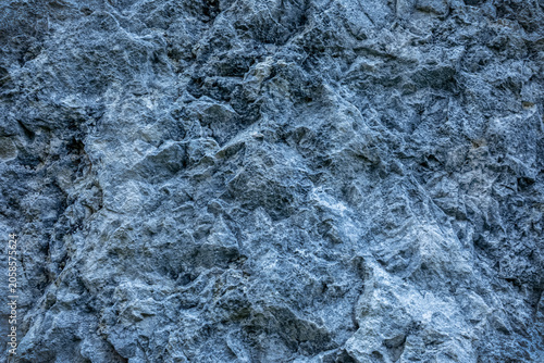 Natural mountain rock wall with sharp relief and deep texture. Seamless stone background with copy space, suitable for design and architectural use.