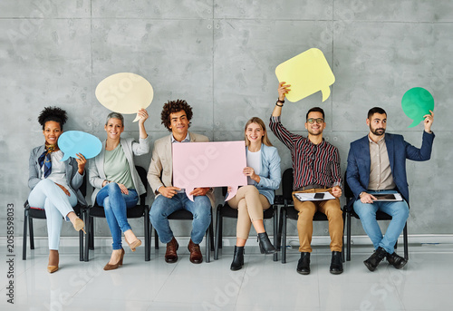 Portrait of a group of young business people in office. Speech bubble, team and comment by business people holding sign, news and voice icon feeling excited on social media. Group, opinion and poll by
