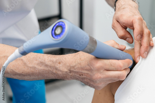 Photography Shock wave therapy treatment on a patient's shoulder with a handheld device in a