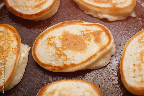 Homemade pancakes frying on pan. Closeup view.